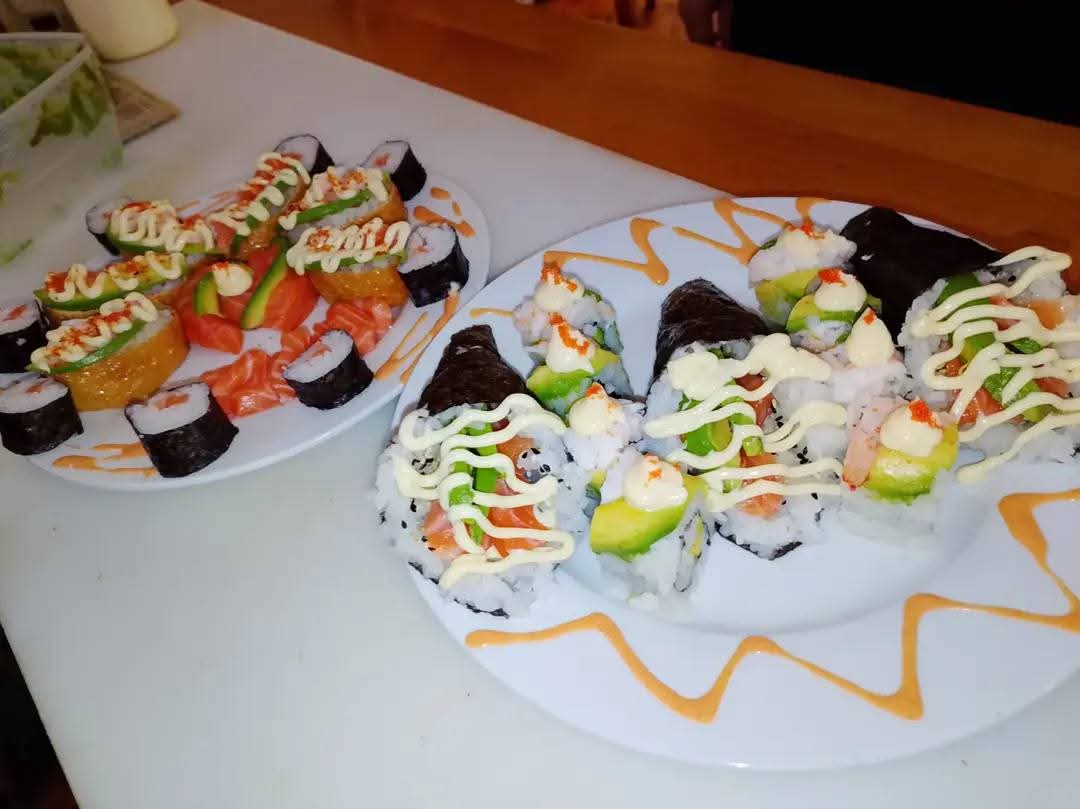 Plates of California rolls, salmon sushi and hand rolls with sauce drizzle